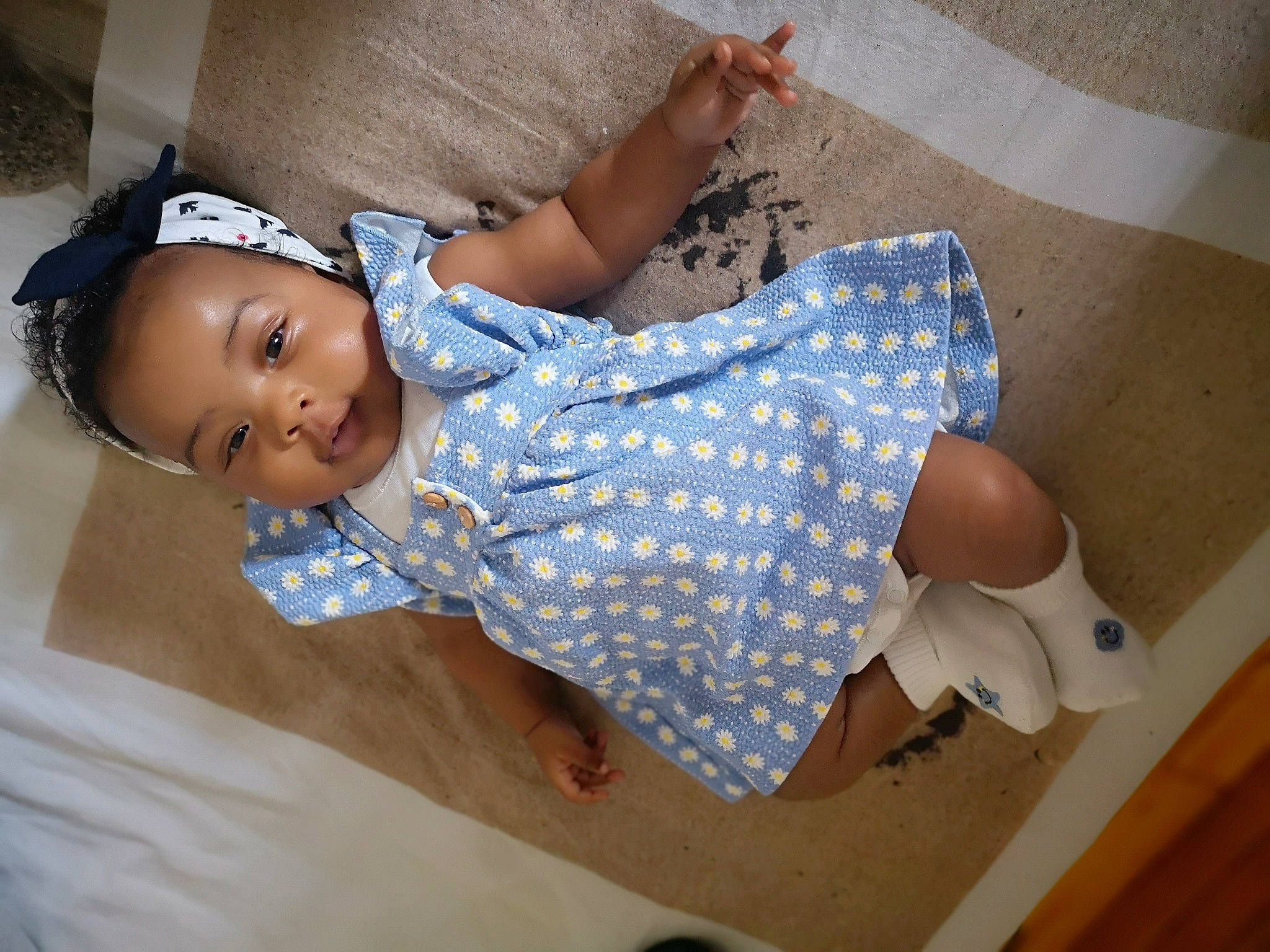 Ava participe au concours pour gagner de l'argent avec cette photo : abdomen, baby, baby_toddler_clothing, comfort, elbow, finger, flooring, happy, headgear, human_leg, linens, pattern, person, skin, sleeve, sock, t_shirt, textile, thigh, toddler