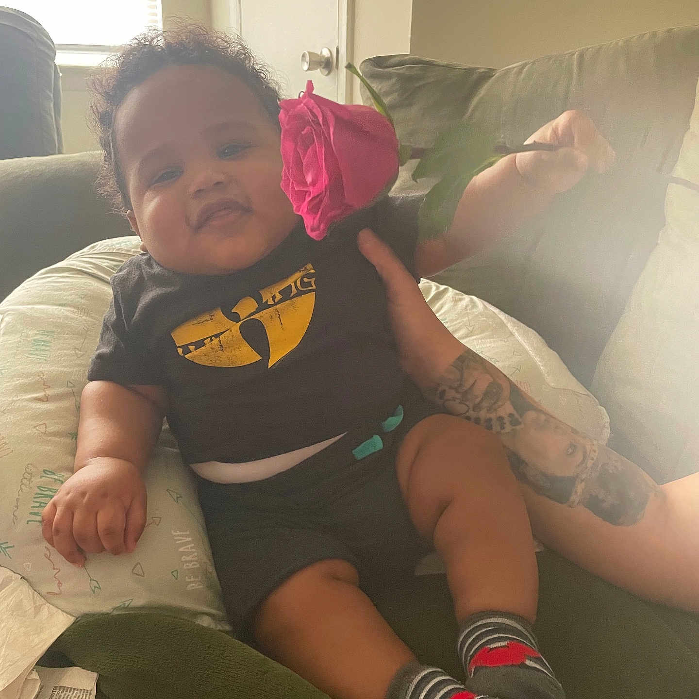 Jayxyus joined the competition — help win amazing prizes! baby, black_tshirt, casual, comfort, couch, curly_hair, cute, face, hand, holding, indoors, infant, person, pillow, relaxing, rose, rose_flower, smile, socks, tattoo