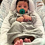 baby, baby_seat, child, closeup, comfort, cozy, cushion, cute, expression, feet, focus, gray_clothing, indoor, infant, pacifier, portrait, resting, small_hands, soft_texture, wide_eyes