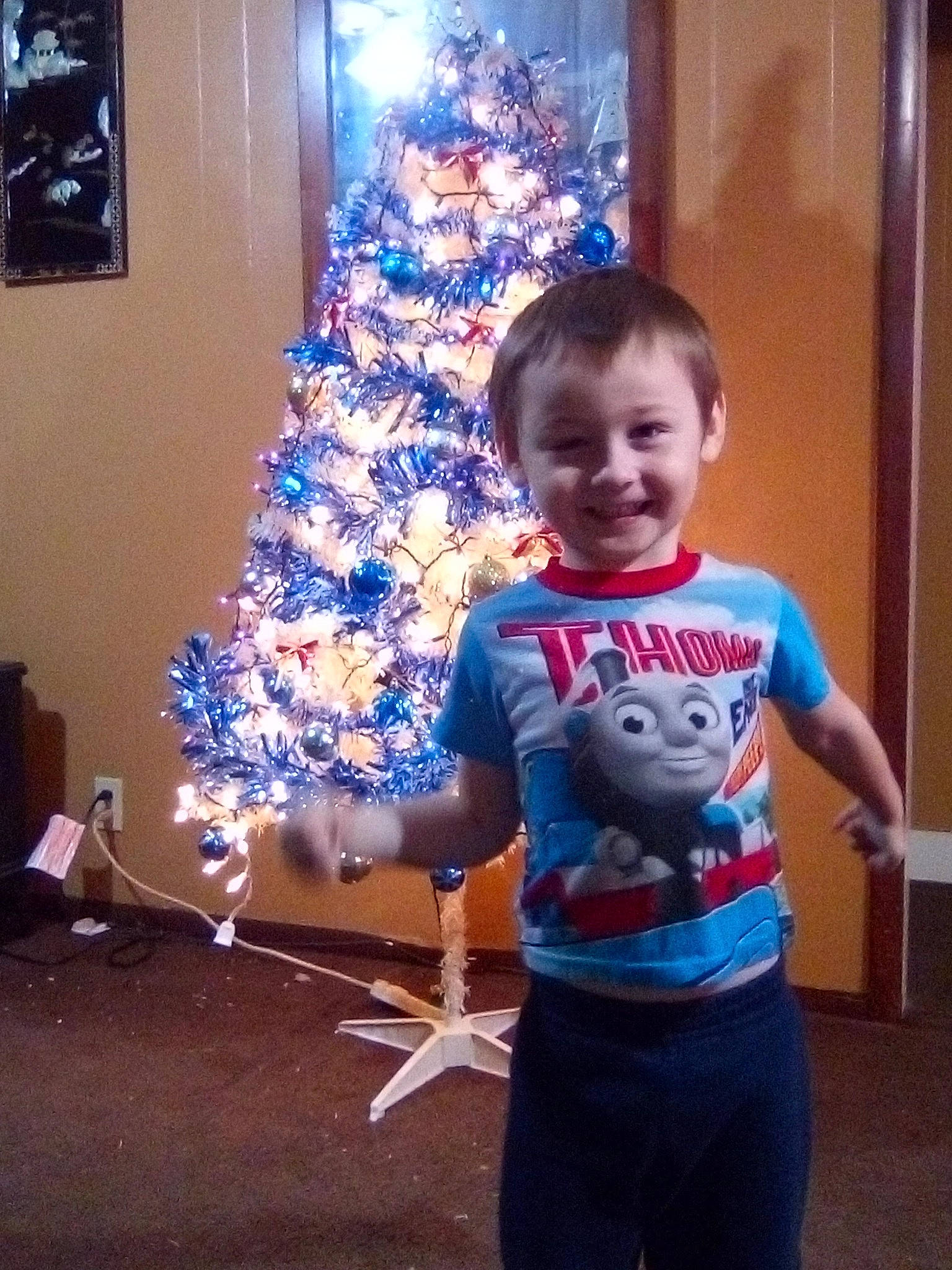 Kiya is registered to the contest to win money with this photo: baby_toddler_clothing, child, christmas, christmas_decoration, christmas_ornament, christmas_tree, electric_blue, event, fun, happy, holiday, holiday_ornament, joy, person, shorts, sleeve, smile, standing, t_shirt, toddler