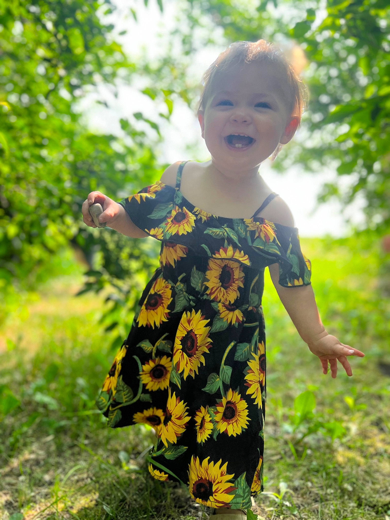 Aspen is registered to the contest to win money with this photo: baby, baby_toddler_clothing, child, dress, face, fun, grass, grassland, happy, head, pattern, people_in_nature, person, plant, prairie, sitting, sleeve, smile, t_shirt, toddler