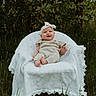 baby, infant, smiling, outdoor, nature, greenery, chair, blanket, headband, knitted_outfit, grass, happy, cute, portrait, sitting, child, person, daylight, forest, leaves