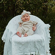 Emery joined the competition — help win amazing prizes! baby, child, outdoor, nature, greenery, grass, chair, blanket, headband, knitted_clothing, smile, portrait, infant, cute, sitting, happy, daylight, forest, young_child, person