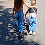 child, children, walking, back_view, siblings, arm_around, toy_stroller, stroller, jeans, denim, sneakers, sandals, pavement, asphalt, shadows, trees, bushes, parked_car, summer, long_hair