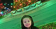 Angèle participe au concours pour gagner de l'argent avec cette photo : child, smiling, coat, hood, christmas_tree, night, lights, outdoor, grass, holiday, festive, decoration, streetlight, happy, person, winter, tree, park, celebration, season
