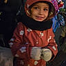 child, smile, coat, hood, mittens, flower_pattern, scarf, night, crowd, festive_lights, outdoor, person, jacket, winter, cold_weather, portrait, happy, colorful, celebration, event
