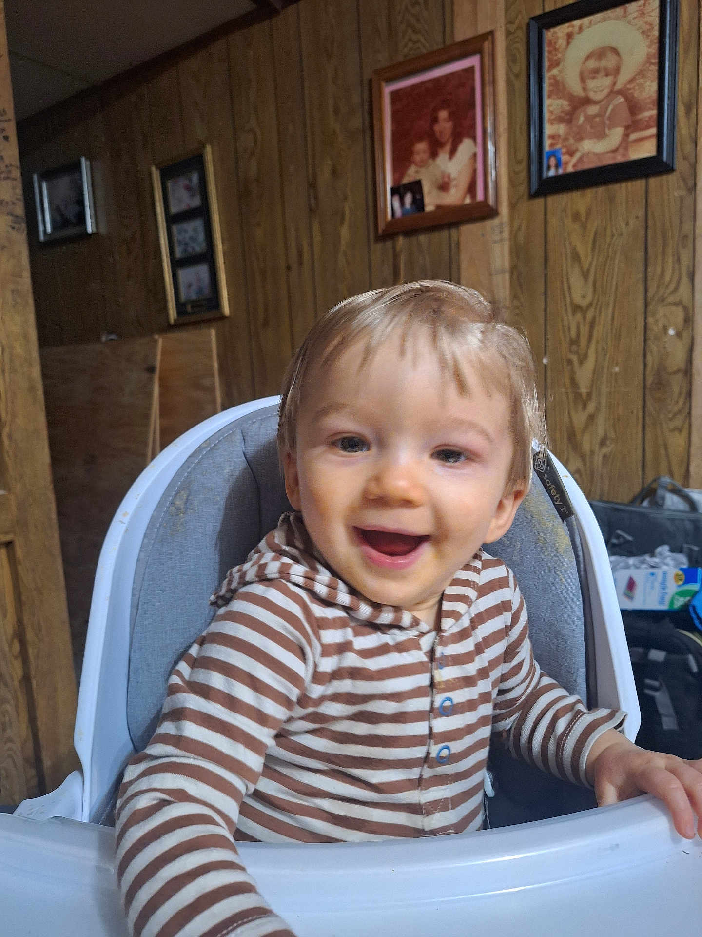 Jaazaniah joined the competition — help win amazing prizes! toddler, child, high_chair, striped_clothing, smiling, happy, indoor, wood_paneling, family_photos, portrait, young_child, baby, person, sitting, casual, cute, home_interior, light, face, infant
