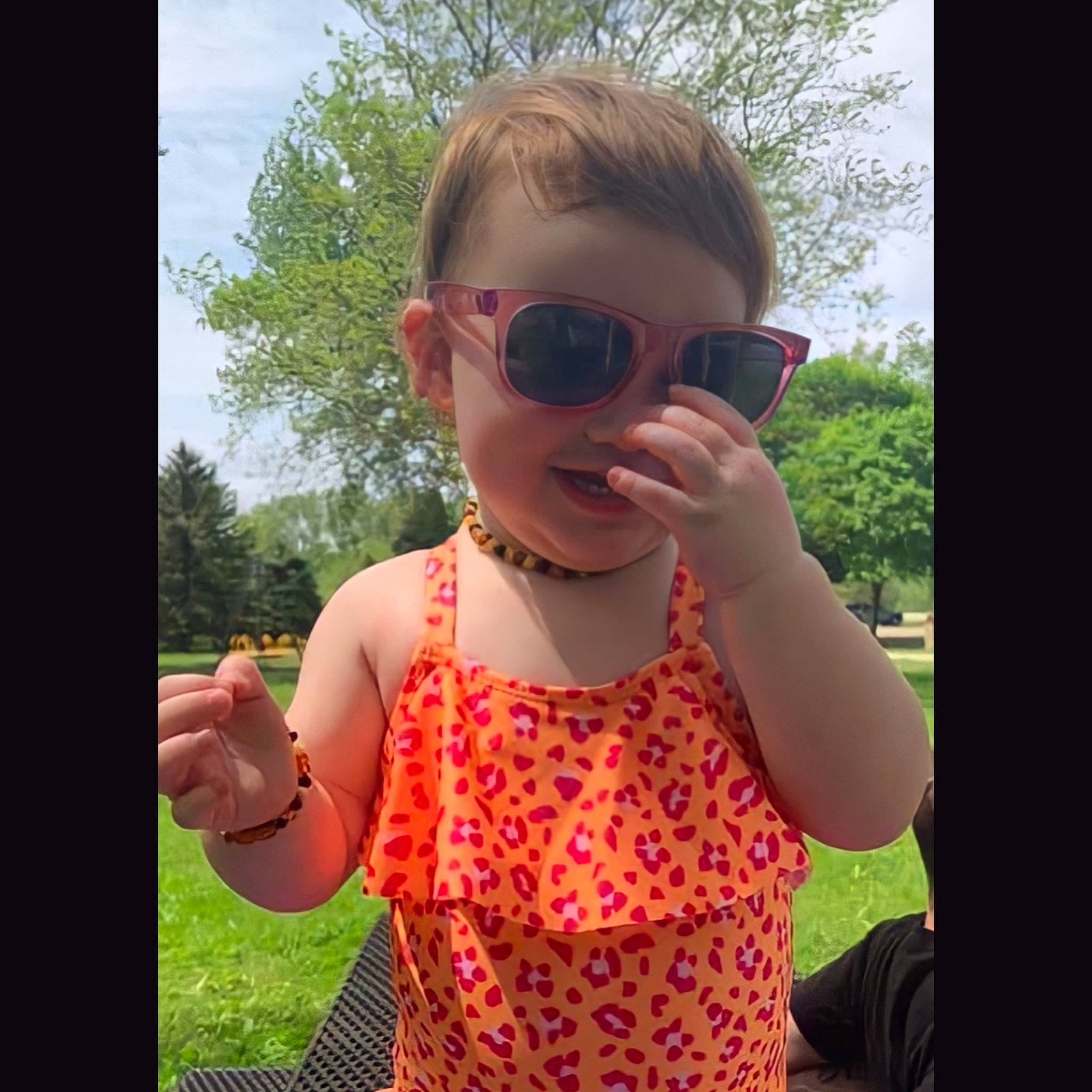 Paislee is registered to the contest to win money with this photo: arm, eyewear, facial_expression, gesture, glasses, goggles, grass, hand, happy, lip, mammal, neck, person, plant, shoulder, skin, sleeve, sunglasses, sunlight, vertebrate