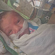 Sincere is registered to the contest to win money with this photo: newborn, baby, hospital, incubator, medical_equipment, nasal_tube, blanket, swaddled, infant, patient, healthcare, premature, care, face, lying_down, closeup, child, person, bed, tubing