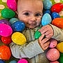 Bentley is registered to the contest to win money with this photo: baby, child, easter_eggs, colorful, plastic_eggs, smiling, curious, indoor, playful, face, hands, clothing, green, pink, yellow, orange, blue, purple, background, soft_surface