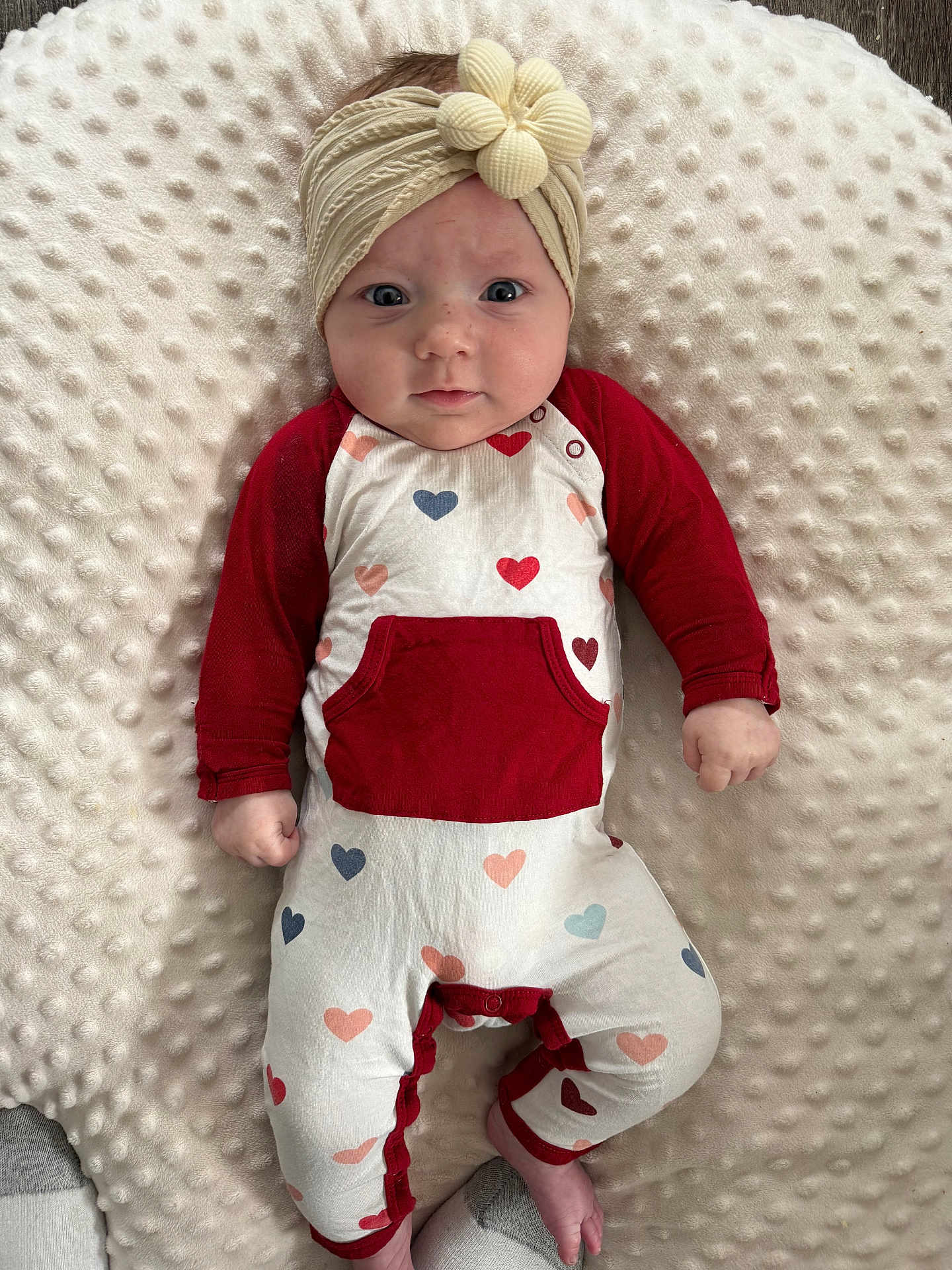 Oaklynn is registered to the contest to win money with this photo: baby, infant, headband, heart_pattern, onesie, blanket, portrait, lying_down, baby_bedding, hands, feet, eyes, cheeks, newborn, adorable, soft_texture, red_sleeves, cozy, gaze, plush_pillow