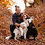 couple, man, woman, dog, border_collie, pet, autumn, leaves, forest, outdoor, hugging, smiling, laughing, portrait, nature, candid, flannel_shirt, black_boots, dog_collar, leaves_on_ground
