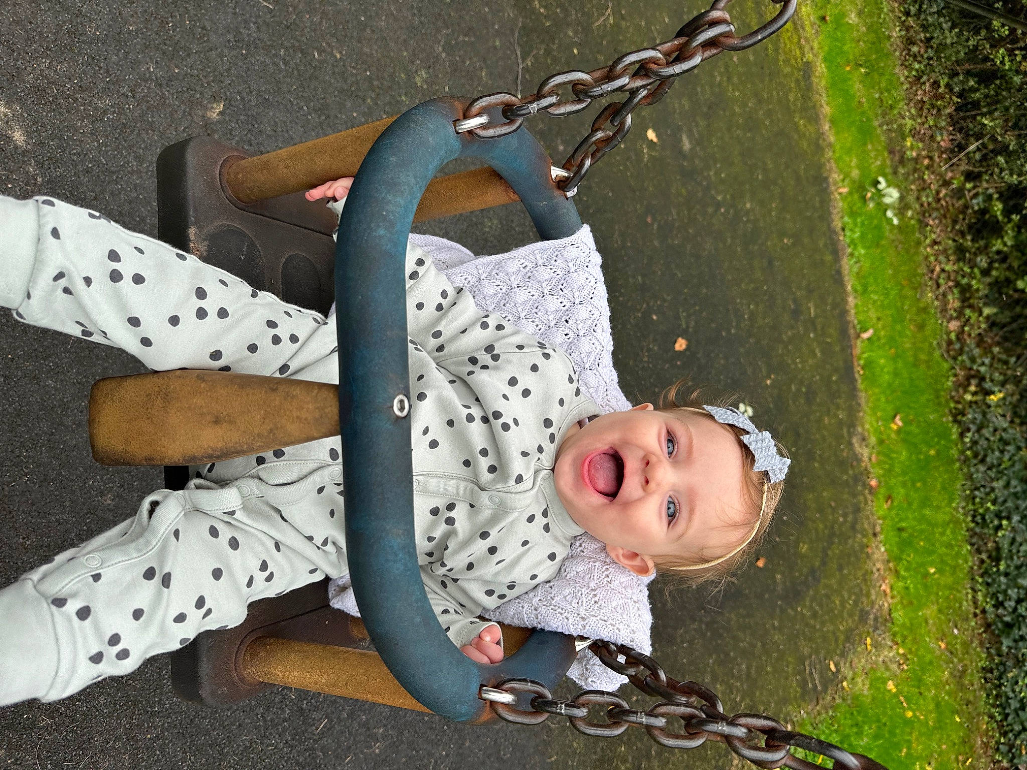 Maggie is registered to the contest to win money with this photo: baby, baby_products, bag, child, circle, fashion_accessory, fun, grass, happy, leisure, luggage_and_bags, pattern, people_in_nature, person, plant, recreation, shoulder_bag, smile, swing, toddler