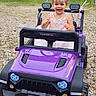 balloons, child, daylight, dress, fun, gravel, greenery, happy, headwear, joy, outdoor, parked, play, playtime, purple, small_vehicle, smiling, toddler, toy_car, vehicle