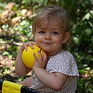 Sofia a rejoint le concours — aidez-le/la à gagner de superbes lots ! toddler, child, yellow_ball, outdoor, greenery, smiling, short_sleeve_shirt, patterned_clothing, grass, nature, play, fun, baby, person, face, hands, summer, sunlight, happy, cute