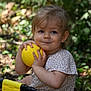 toddler, child, yellow_ball, outdoor, greenery, smiling, short_sleeve_shirt, patterned_clothing, grass, nature, play, fun, baby, person, face, hands, summer, sunlight, happy, cute