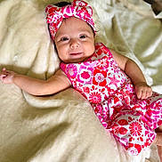 Skye joined the competition — help win amazing prizes! baby, infant, smile, headband, floral_pattern, blanket, soft_texture, clothing, cute, lying_down, happy, skin, arm, hand, face, indoors, portrait, child, young, adorable