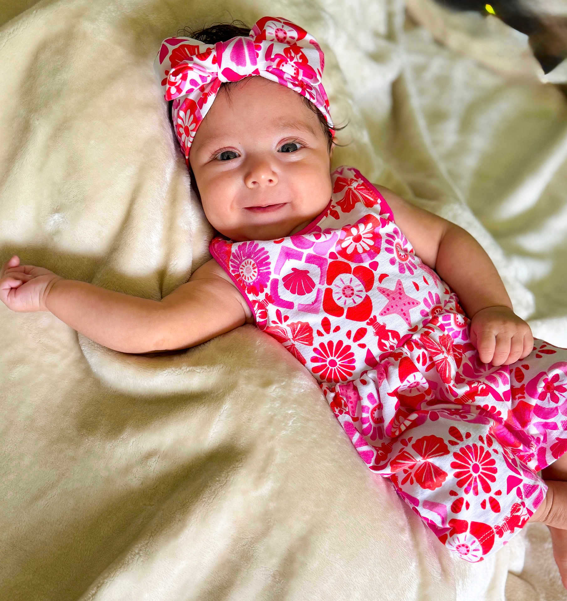 Skye joined the competition — help win amazing prizes! baby, infant, smile, headband, floral_pattern, blanket, soft_texture, clothing, cute, lying_down, happy, skin, arm, hand, face, indoors, portrait, child, young, adorable