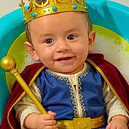 Antonio is registered to the contest to win money with this photo: baby, child, crown, king, costume, scepter, cape, blue_outfit, smiling, bubbles, tub, golden, portrait, happy, indoor, cute, infant, seated, playful, royalty