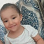 beige_pattern, blue_pattern, cheerful, child, cushion, cute, face, happy, head, indoor, patterned_clothing, person, portrait, seated, skin, small_child, smiling, toddler, white_shirt, young_child