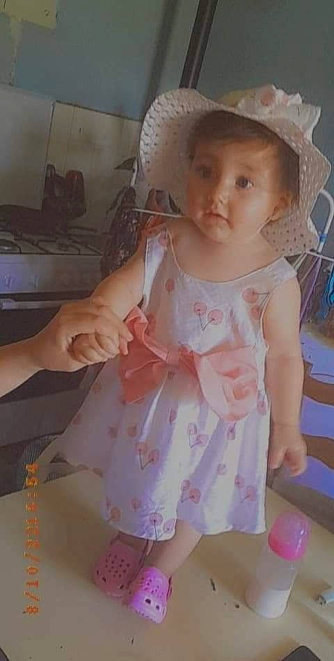 Aliana participe au concours pour gagner de l'argent avec cette photo : baby, baby_products, baby_toddler_clothing, cheek, child, day_dress, dress, embellishment, fashion_accessory, hand, happy, headgear, one_piece_garment, pattern, person, pink, sitting, skin, sleeve, sun_hat