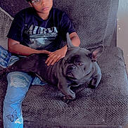 Mayweather is registered to the contest to win money with this photo: person, dog, french_bulldog, glasses, tshirt, nirvana, jeans, butterfly, chair, furniture, indoor, relaxed, pet, casual, sitting, black_dog, ripped_jeans, wood_floor, home, comfort