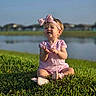 Aria joined the competition — help win amazing prizes! child, toddler, baby, girl, portrait, outdoor, grass, lake, water, nature, sunlight, pink_dress, headband, bow, shoes, sitting, smiling, playful, daylight, landscape