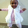toddler, child, girl, smiling, indoor, white_vest, pink_clothing, headband, boots, happy, standing, floor, wall, cute, portrait, baby, person, fashion, apparel, playful