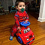 blue_steering_wheel, child, curtains, floor, furniture, happy, hardwood_floor, home, indoor, mismatched_socks, pacifier, person, playtime, red_toy, smiling, socks, spiderman_pajamas, toddler, toy_car, young_child