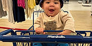 Marlon is registered to the contest to win money with this photo: apparel, baby, bear_sweater, blue_hat, child, clothes, clothing_store, cute, flooring, happy, indoor, infant, person, racks, retail, shopping, shopping_cart, smiling, socks, store