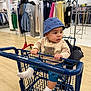 Marlon is registered to the contest to win money with this photo: apparel, baby, blue_hat, child, clothing_rack, cute, flooring, footwear, hands, indoor, infant, person, retail, seat, shopping, shopping_cart, socks, store, sweater, teddy_bear
