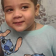 Norma is registered to the contest to win money with this photo: child, girl, smile, hair_bow, blue_shirt, cartoon_character, stitch, portrait, face, earrings, necklace, indoor, background, wallpaper, playful, cute, clothing, young, happy, person