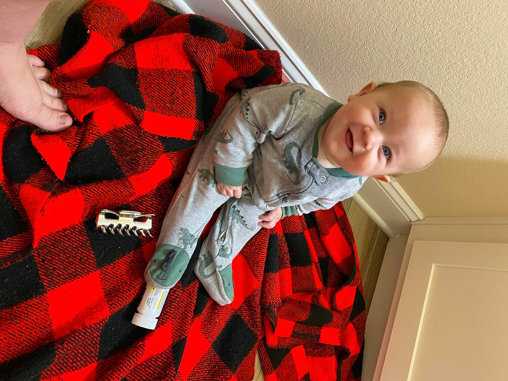 Owen is registered to the contest to win money with this photo: baby, baby_products, baby_toddler_clothing, carmine, collar, comfort, costume, fashion_accessory, hand, joy, linens, orange, pattern, person, plaid, red, room, sleeve, smile, tartan
