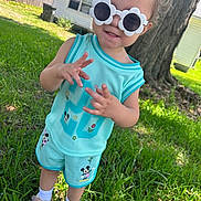 Joselyn joined the competition — help win amazing prizes! toddler, child, sunglasses, flower_shaped, turquoise_clothing, mickey_mouse, shorts, tank_top, grass, tree, house, outdoor, shoes, socks, sunny, daylight, playful, gesture, smile, person