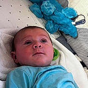 Oliver joined the competition — help win amazing prizes! baby, infant, blue_shirt, stuffed_animal, bed, blanket, pillow, curious, lying_down, indoor, soft_toys, child, cute, young, portrait, face, person, cozy, comfort, resting