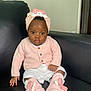 Chimamanda joined the competition — help win amazing prizes! baby, infant, child, pink_clothing, headwrap, socks, bow, couch, black_leather, white_shorts, buttoned_cardigan, indoor, portrait, cute, curious, seated, face, hand, footwear, soft_lighting