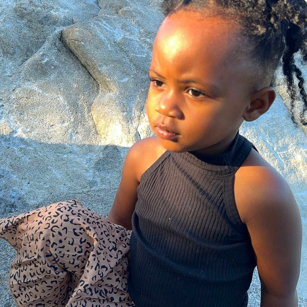 Savayah is registered to the contest to win money with this photo: black_top, casual_clothing, child, curly_hair, cute, daylight, fashion, leopard_print_pants, nature, outdoor, person, portrait, rock, serious_expression, sitting, socks, sunlight, toddler, white_shoes, young_girl