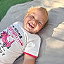 Landry joined the competition — help win amazing prizes! baby, blanket, blonde_hair, child, clothing, cute, face, happy, joyful, laying_down, outdoor, person, portrait, red_shorts, skin, smiling, sunlight, toddler, tshirt, young_child