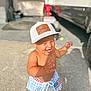 american_flag, bare_chest, cap, casual, child, concrete, daylight, footwear, happy, hat, house, outdoor, person, playful, shorts, smiling, summer, sunlight, toddler, vehicle