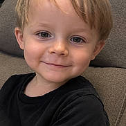 Oakley joined the competition — help win amazing prizes! child, toddler, portrait, smiling, happy, sitting, couch, indoor, black_shirt, blond_hair, brown_eyes, face, head, arm, casual, home, furniture, close_up, photography, adorable