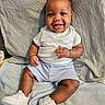 A'Mir is registered to the contest to win money with this photo: baby, smiling, sitting, white_shoes, nike, shorts, tshirt, infant, cute, happy, child, indoors, blanket, soft_texture, portrait, casual_clothing, feet, hand, face, young