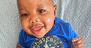 A'Mir is registered to the contest to win money with this photo: baby, smiling, blue_shirt, converse, all_star, child, cute, happy, portrait, infant, face, skin, eyes, tongue, hand, clothing, soft_blanket, lying_down, indoor, closeup