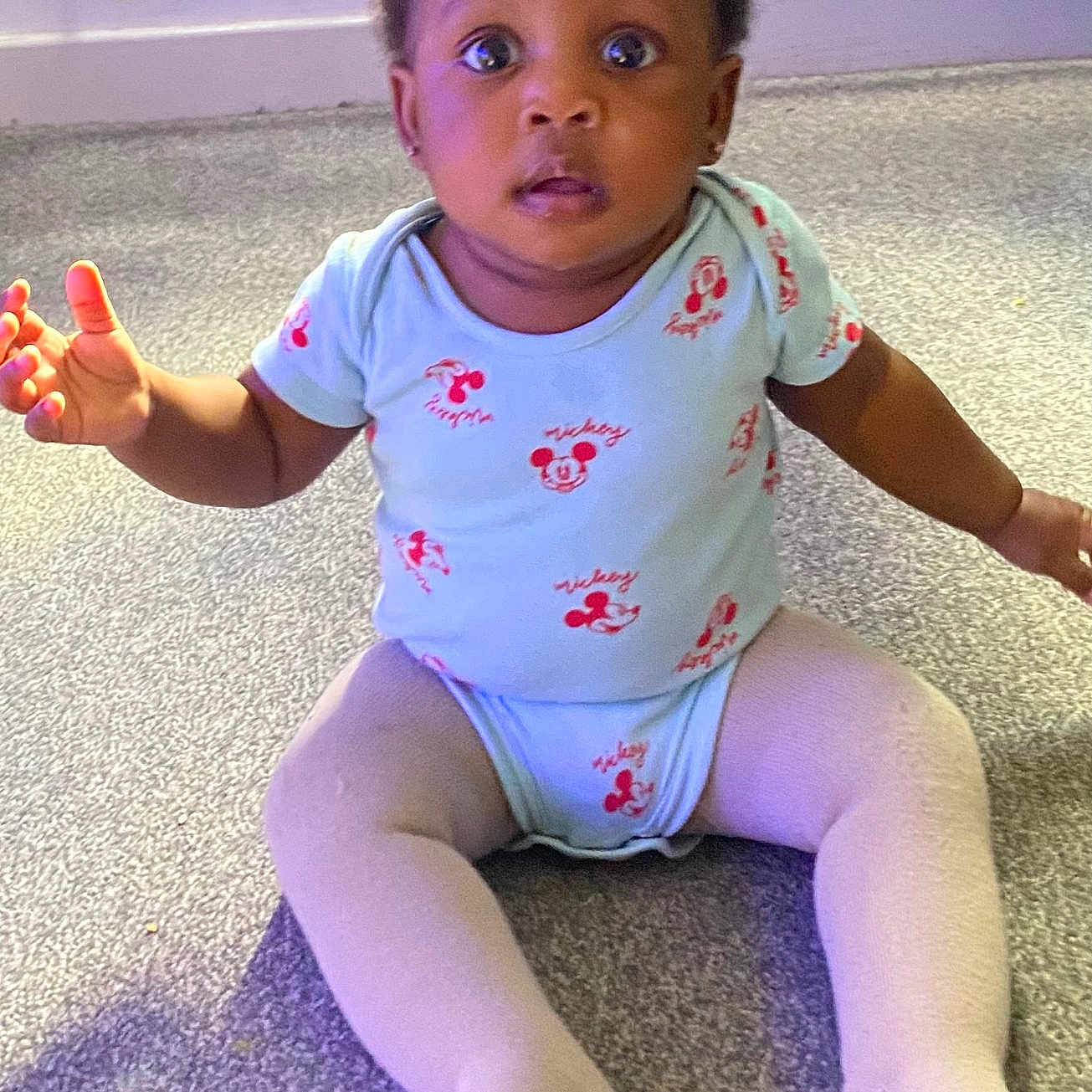 Gloria joined the competition — help win amazing prizes! baby, carpet, child, clothing, curious, cute, expression, floor, home, indoor, infant, looking, mickey_mouse, onesie, person, portrait, radiator, sitting, tights, young_child