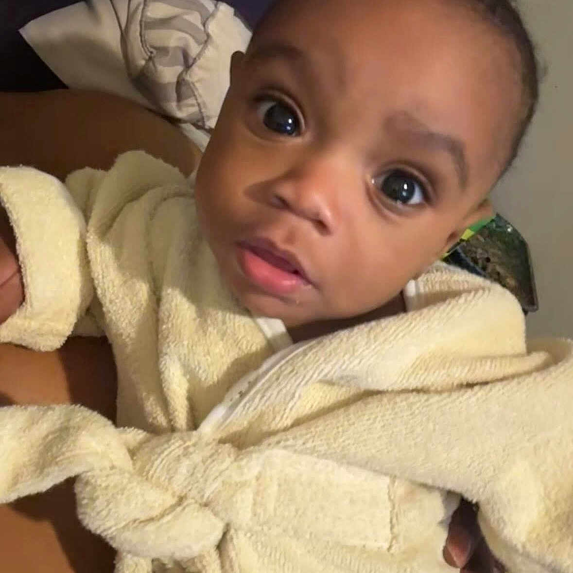 Jahmezze is registered to the contest to win money with this photo: baby, child, closeup, clothing, cozy, curious, cute, expression, eyes, face, hand, indoor, infant, person, portrait, robe, skin, soft, towel, young