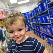 Baylen is registered to the contest to win money with this photo: aisle, baby, blue_bins, casual_wear, child, clothing, cute, happy, indoor, person, playful, retail, shopping, shopping_cart, short_hair, smiling, store, striped_shirt, toddler, young_child