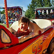 Malik participe au concours pour gagner de l'argent avec cette photo : amusement_ride, carnival, child, daytime, fair, fun, game_stalls, happy, number_95, outdoor, person, playful, plush_toys, red, smiling, sunlight, toddler, toy_car, trees, yellow