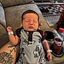 newborn, baby, sleeping, infant, tattoo, arm, clothing, recliner, sofa, bottle, drink, living_room, person, hand, cute, resting, indoors, comfort, peaceful, casual