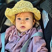 Emma a rejoint le concours — aidez-le/la à gagner de superbes lots ! baby, blue_eyes, car_seat, child, closeup, clothing, crocheted_hat, curious, cute, face, hat, headwear, indoors, person, pink_jacket, portrait, sitting, straps, toddler, young_child