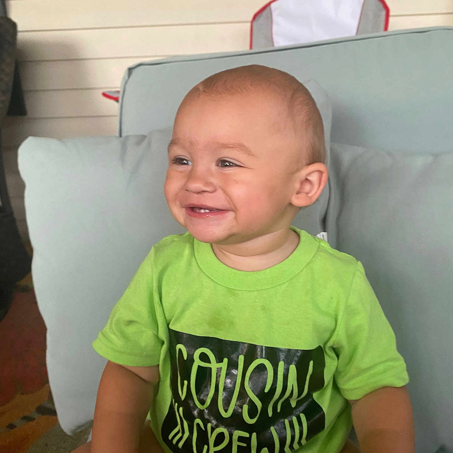 August is registered to the contest to win money with this photo: baby, bodypart, clothing, couch, cushion, face, furniture, happy, head, homedecor, laughing, mouth, person, photography, pillow, portrait, sitting, smile, t_shirt, teeth