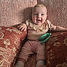 baby, infant, smiling, couch, pink, cushions, toy, teething_toy, happy, indoor, child, portrait, cozy, clothing, socks, furniture, home, cute, person, seated